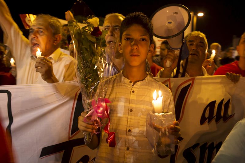 © Reuters. A boy holds a candle and flowers as he attends a protest to condemn the attack by a gunman at the beach of the Imperial Marhabada hotel in Sousse