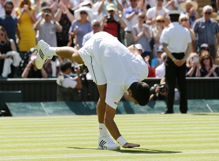 © Reuters. Novak Djokovic toca na grama após vitória sobre Philipp Kohlschreiber na estreia em Wimbledon