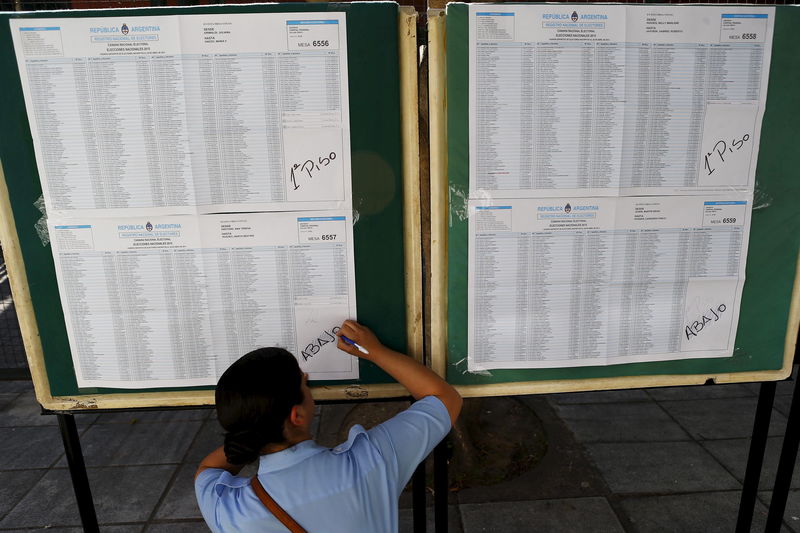 © Reuters. A police officer writes on a national voter registration list in a voting station during the presidential election at Buenos Aires, Argentina