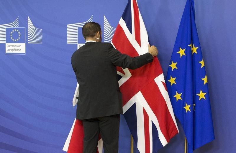 © Reuters. An employee at the European Commission adjusts a British flag ahead of the meeting between Prime Minister Cameron and European Commission President Juncker in Brussels