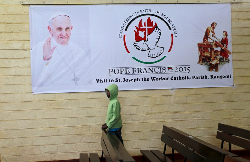 © Reuters. A boy is pictured below a banner of Pope Francis before a special mass at St. Joseph the Worker Catholic Parish where Pope Francis is expected to visit within Kangemi Kenya