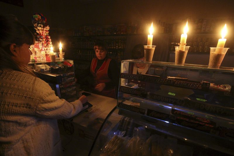 © Reuters. A customer visits a grocery lit with candles due to a power cut, in Simferopol, Crimea