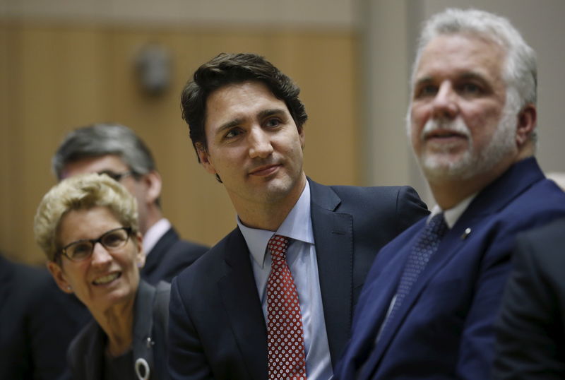 © Reuters. Canada's PM Trudeau sits with Ontario Premier Wynne and Quebec Premier Couillard during the First Ministers' meeting in Ottawa