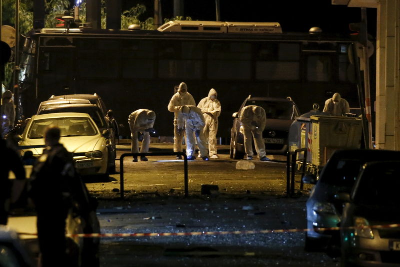 © Reuters. Forensic experts search for evidence on a street where a bomb exploded outside the entrance of the Hellenic Business Federation offices in Athens