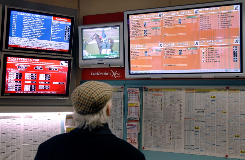 © Reuters. A man watches television screens in a Ladbrokes bookmaker in London