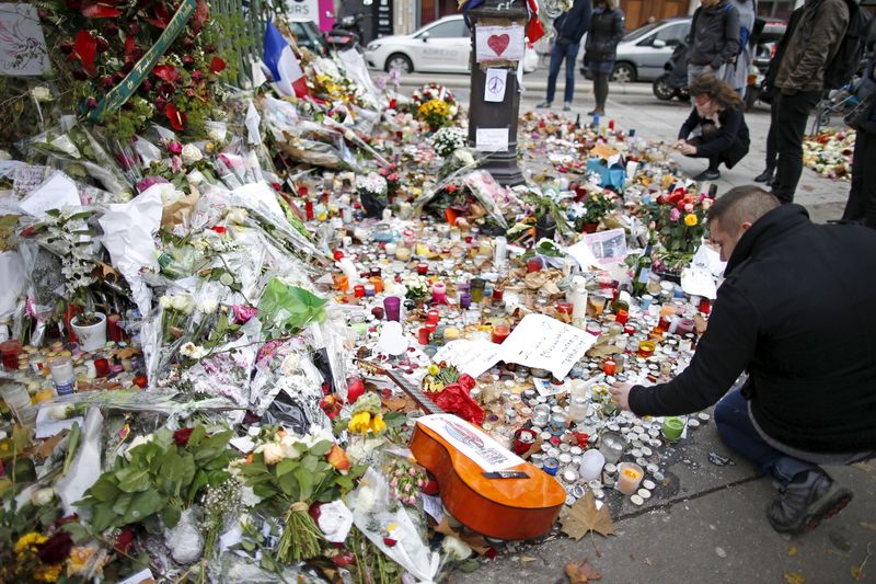 © Reuters. Pessoas diante de flores e outros objetos em local de ataques em Paris