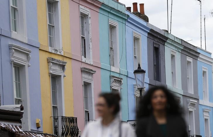 © Reuters. Pedestrians walk past a row of houses in London