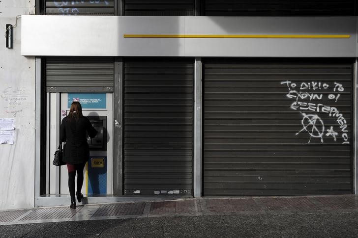 © Reuters. A woman uses an ATM outside a National Bank branch in Athens