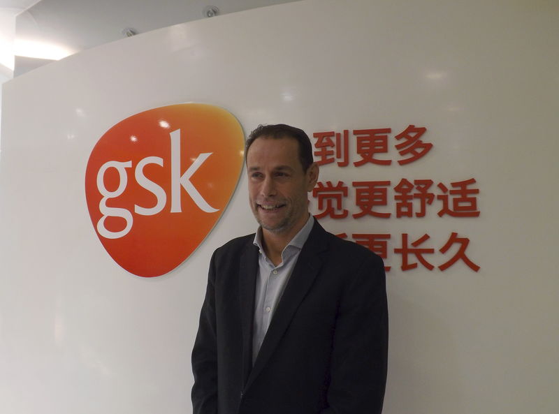 © Reuters. Herve Gisserot, general manager for GSK China, poses for a photograph in front of a company logo during an interview with Reuters at an office in Shanghai