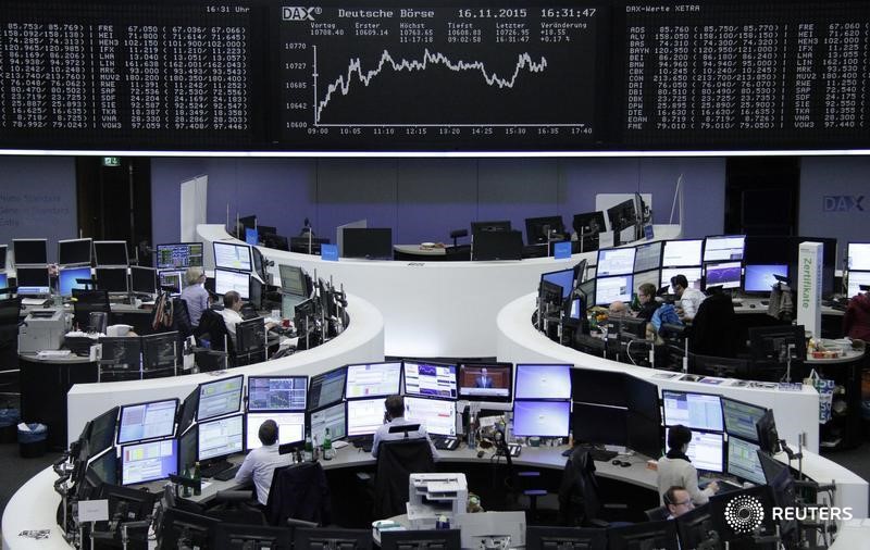 © Reuters. Traders work at their screens in front of the German share price index DAX board at the stock exchange in Frankfurt
