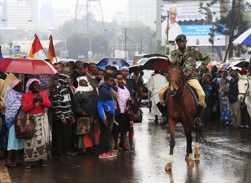 © Reuters. A policeman on horseback keeps watch over members of the Catholic faith waiting to attend a mass led by Pope Francis at the University of Nairobi in Kenya's capital Nairobi