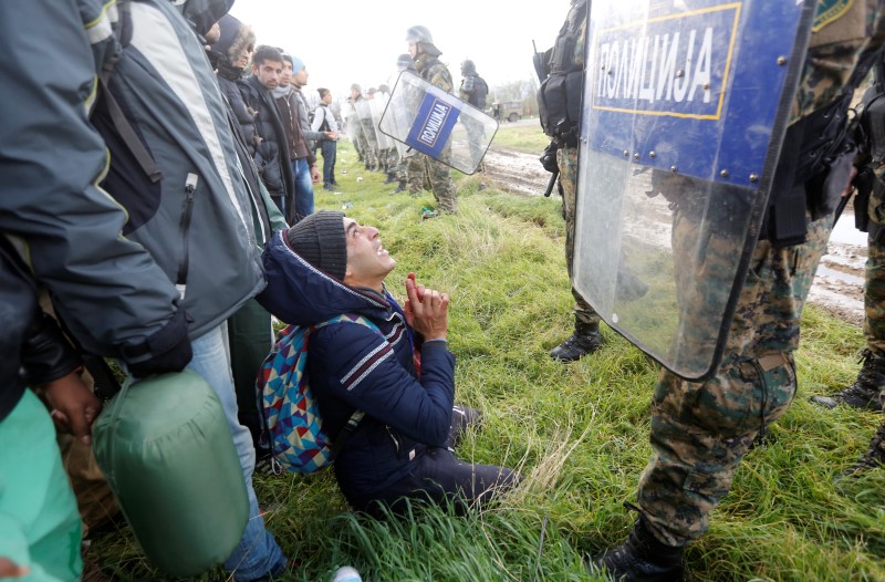 © Reuters. A migrant begs Macedonian police officers as he tries to cross the Greek-Macedonian border near the Greek village of Idomeni