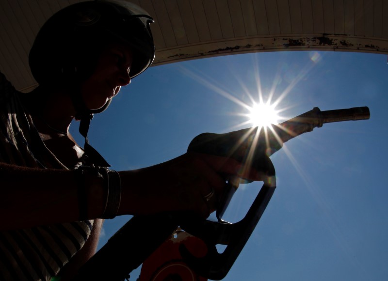 © Reuters. A customer uses a petrol nozzle in a gas station in Nice