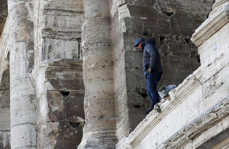 © Reuters. رجل يتسلق كولوسيوم روما احتجاجا على حملة خلال احتفالات السنة المقدسة