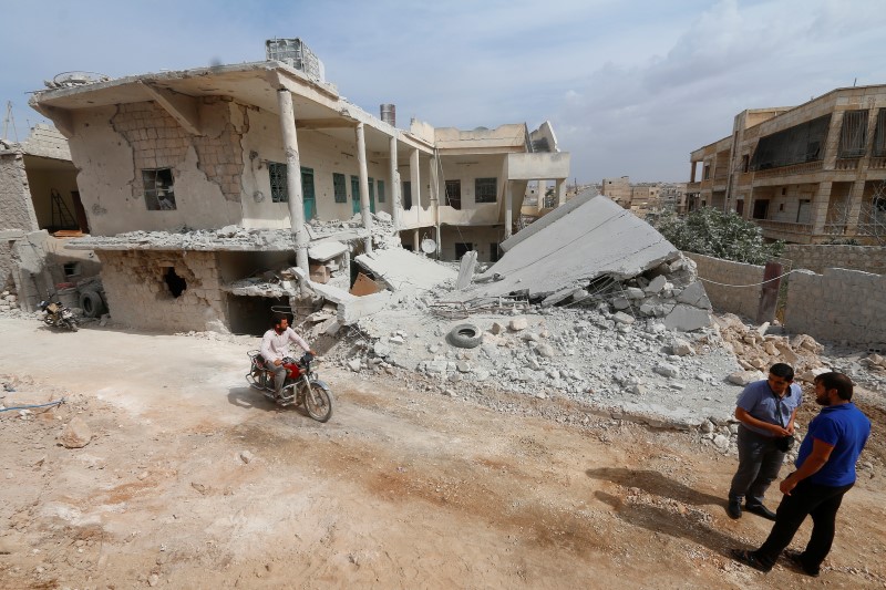 © Reuters. A man drives a motorcycle near a site hit by what residents said were airstrikes carried out by the Russian air force in the town of Darat Izza, in Aleppo province