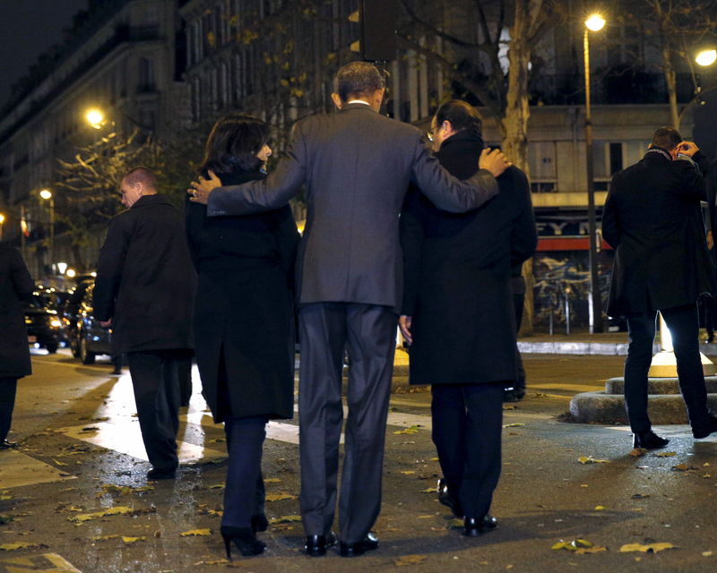© Reuters. U.S. President Barack Obama, French President Francois Hollande (R) and Paris Mayor Anne Hidalgo (L) walk away after placing flowers at a makeshift memorial to pay tribute to the victims of the Paris attacks at the Bataclan in Paris 