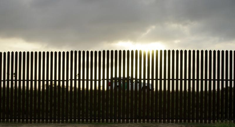 © Reuters. A U.S. Border Patrol vehicle drives by the 18-foot (five-metre) high rusty steel barrier along the U.S.-Mexico border at sunset in Brownsville, Texas