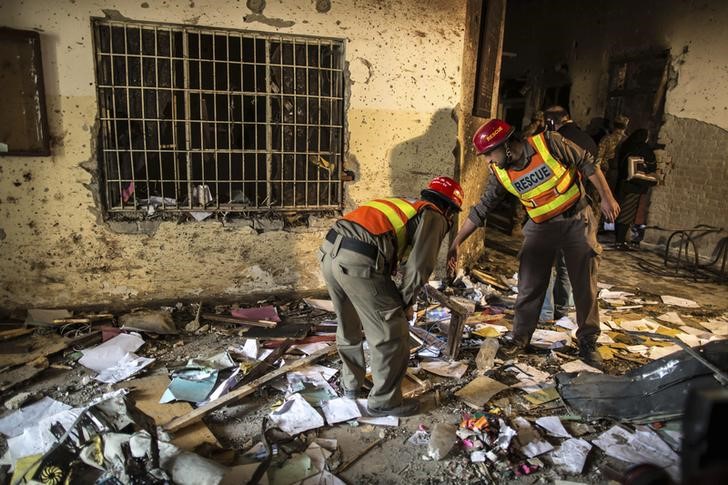 © Reuters. Rescue team members go through debris inside the Army Public School, which was attacked by Taliban gunmen, in Peshawar