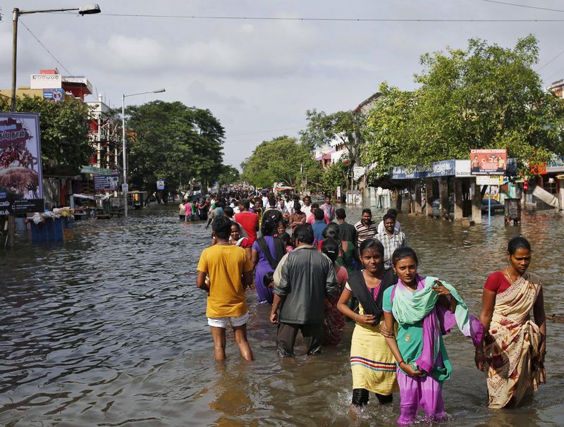 © Reuters. Residents wade through a flooded street as they evacuate their homes in Chennai, India