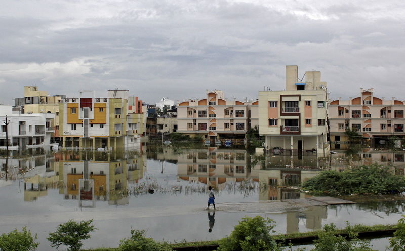 © Reuters. A man walks through a flooded residential area in Chennai