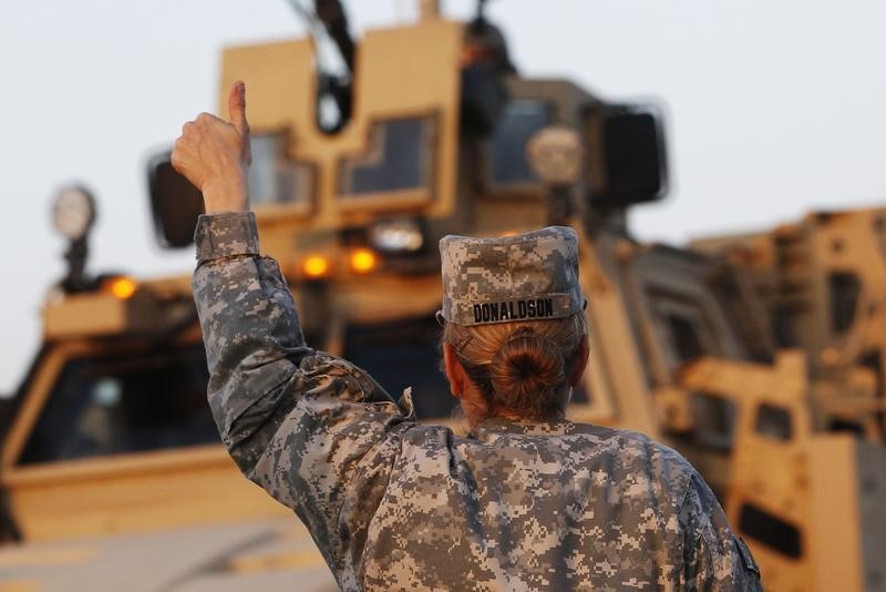 © Reuters. Американская военнослужащая разрешает проезд конвою на границе Кувейта и Ирака