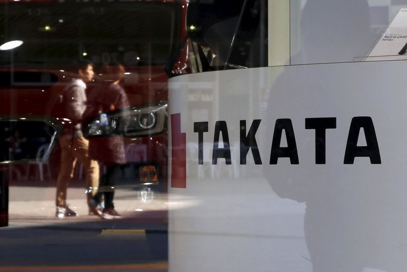 © Reuters. A logo of Takata Corp is seen with its display as people are reflected in a window at a showroom for vehicles in Tokyo