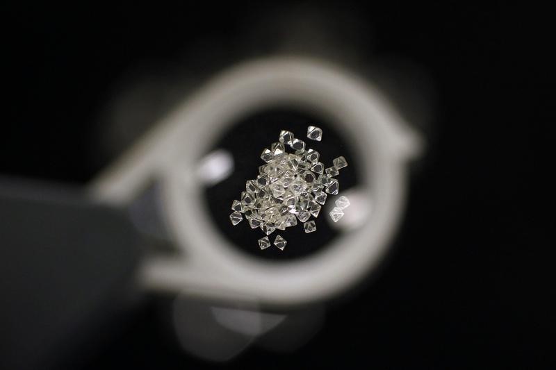 © Reuters. Uncut diamonds from southern Africa and Canada are seen through a jeweller's loupe at De Beers headquarters in London
