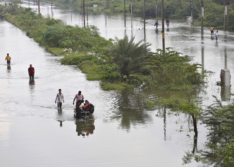 © Reuters. Displaced residents wade through a flooded street besides a flooded railway track in the flood-affected areas Chennai, India 