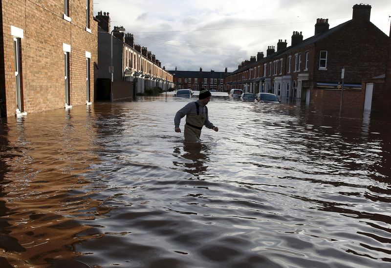 © Reuters. A local man wades through flood water on a residential street in Carlisle, Britain