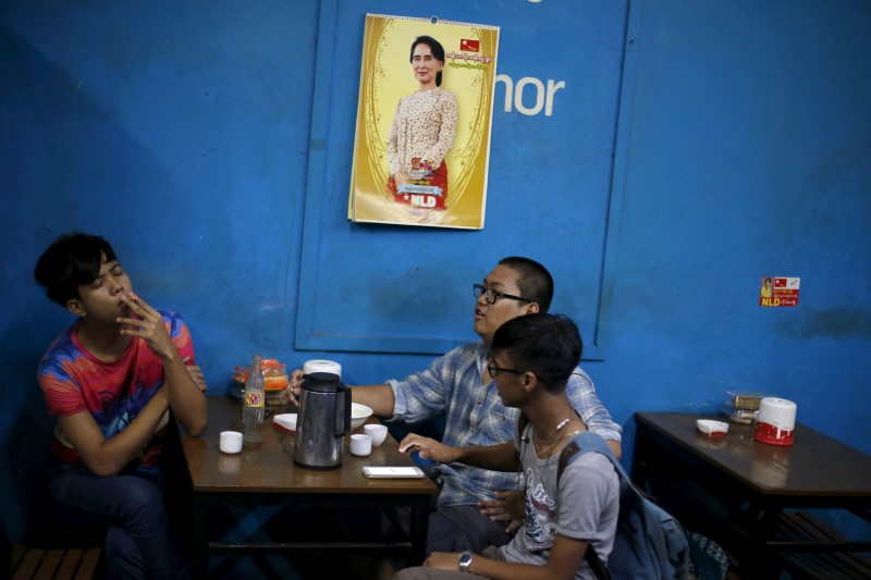 © Reuters. Men sit in a tea house under a calendar with a picture of Aung San Suu Kyi in Yangon 