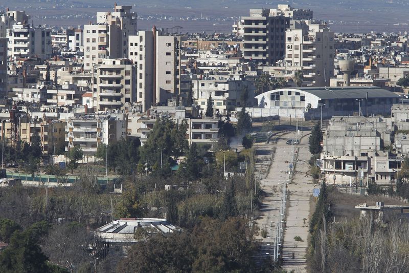 © Reuters. Decenas de personas salen de la zona rebelde de Homs bajo un acuerdo de paz