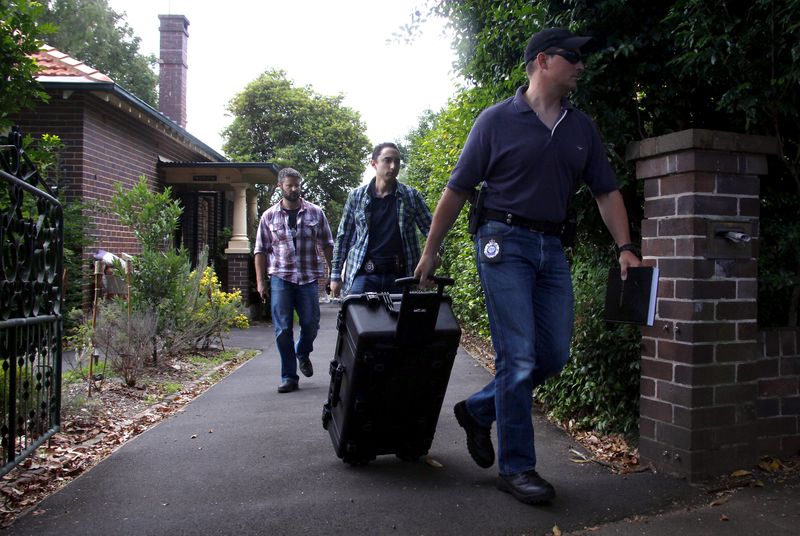 © Reuters. Australian Federal Police officers walk down the driveway after searching the home of probable creator of cryptocurrency bitcoin Craig Steven Wright in Sydney's north shore