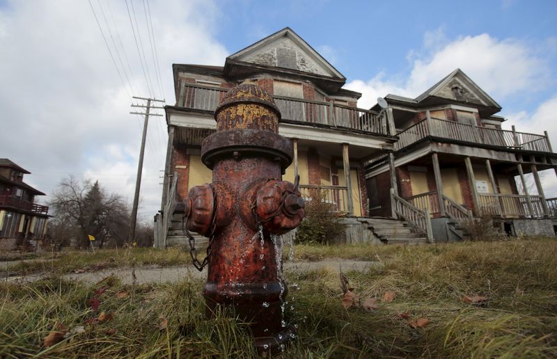 © Reuters. Water leaks from a fire hydrant in front of two boarded-up, vacant houses in a once vibrant neighborhood in Detroit