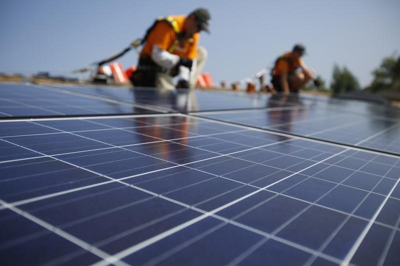 © Reuters. Vivint Solar technicians install solar panels on the roof of a house in Mission Viejo