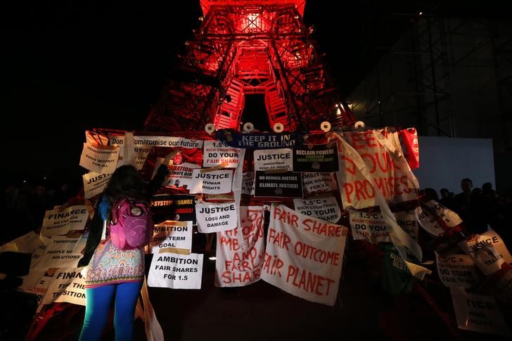 © Reuters. Mulher fixa cartaz durante manifestação em frente a uma réplica da Torre Eiffel