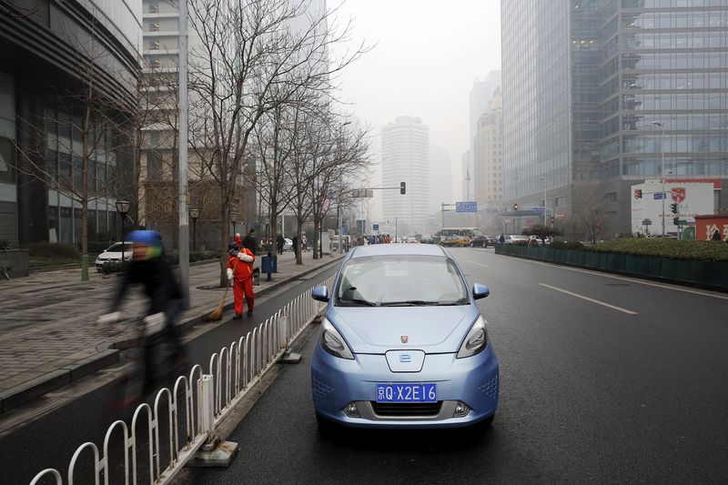 © Reuters. A Roewe E50 electric car is parked next to a street as a bicycle travels past amid heavy smog in Beijing