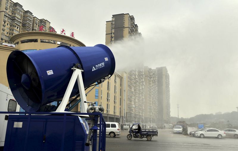 © Reuters. A "mist cannon" works alongside a street on a smoggy day in Changsha