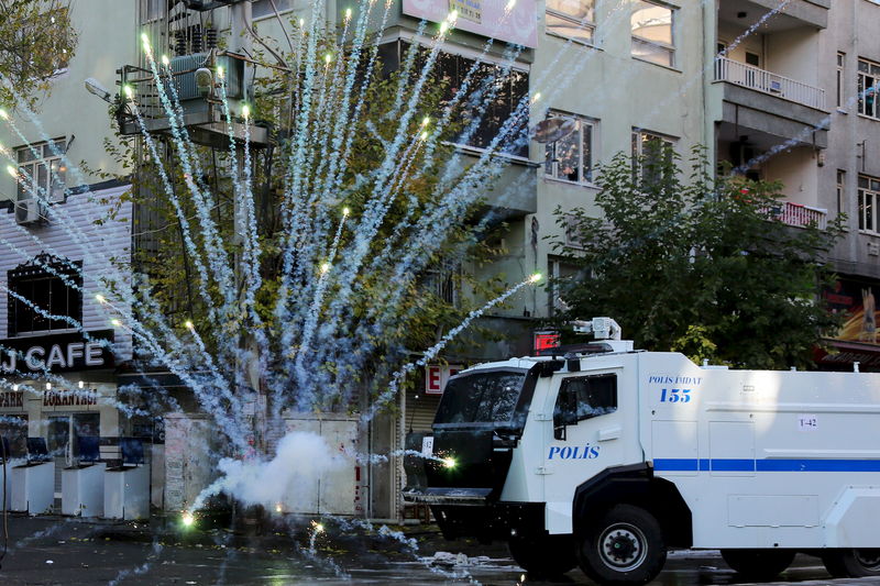 © Reuters. Riot police use water cannon as demonstrators throw fireworks during a protest against the curfew in Sur district, in the Kurdish dominated southeastern city of Diyarbakir, Turkey