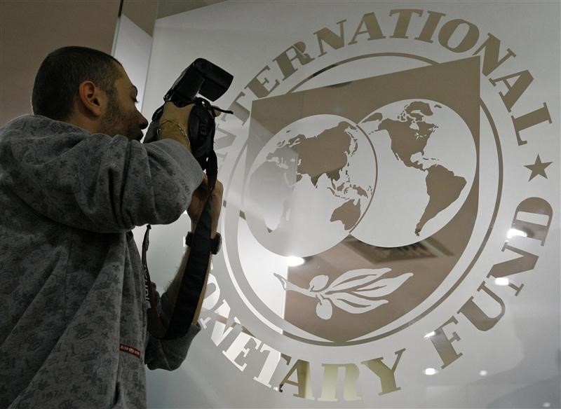 © Reuters. A photographer takes pictures through a glass carrying the International Monetary Fund logo during a news conference in Bucharest