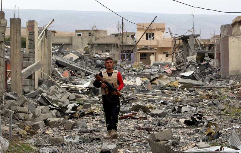 © Reuters. A volunteer from the Yazidi sect who have joined the Kurdish peshmerga forces walks with his weapon in the town of Sinjar