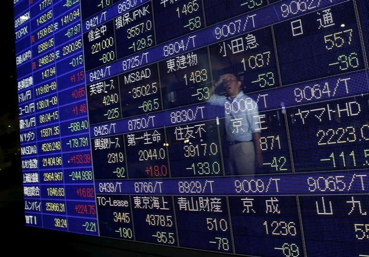 © Reuters. A man is reflected on a display showing stock quotation board outside a brokerage in Tokyo 