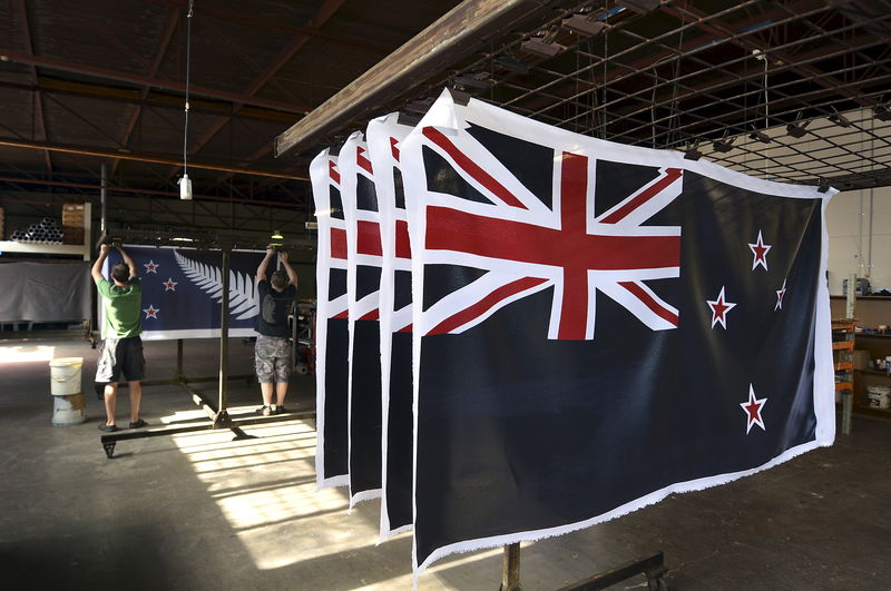 © Reuters. Factory workers Garth Price and Andrew Smith hang new designs of the national flag of New Zealand at a factory in Auckland, New Zealand