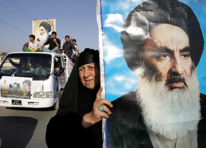 © Reuters. An Iraqi woman displays huge poster of Shi'ite religious leader Grand Ayatollah Ali al-Sistani during rally in Sadr City.