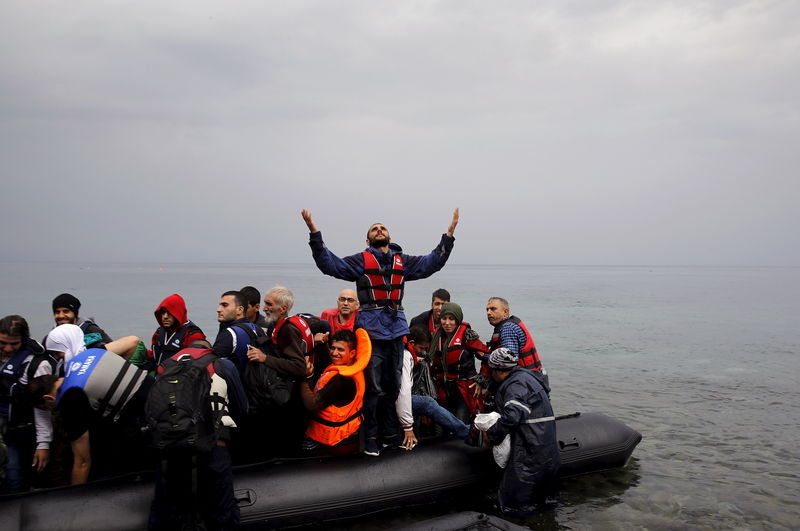 © Reuters. A Syrian refugee gives thanks to God as he arrives in an overcrowded dinghy on the Greek island of Lesbos after crossing part of the Aegean Sea from Turkey