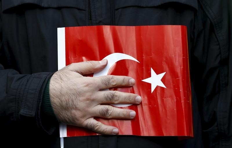 © Reuters. Supporter of Gulen movement holds a Turkey's national flag during a protest outside the Kanalturk and Bugun TV building in Istanbul