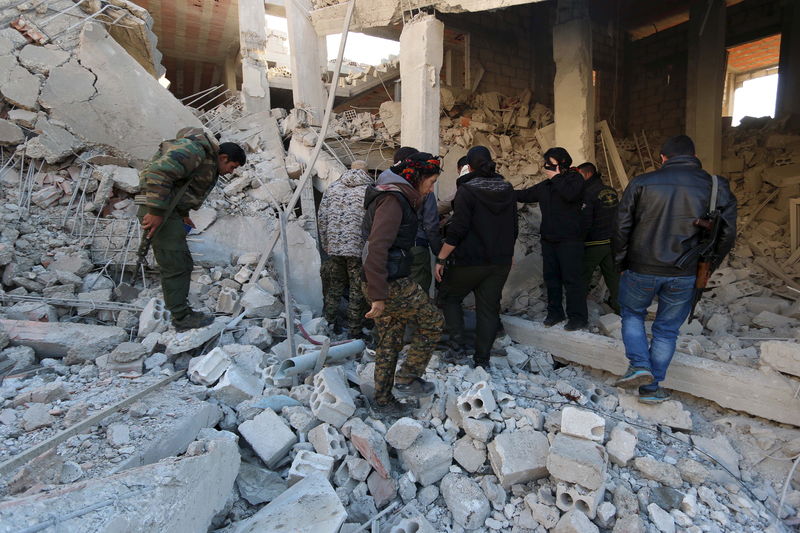 © Reuters. Kurdish fighters from the People's Protection Units (YPG) inspect damage at a site hit by one of three truck bombs, in the YPG-controlled town of Tel Tamer, Syria 