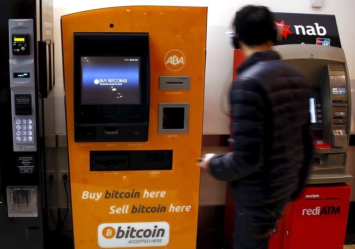 © Reuters. A customer of an Australian bank walks away after withdrawing money from an Automatic Teller Machine located next to a Bitcoin ATM in central Sydney, Australia