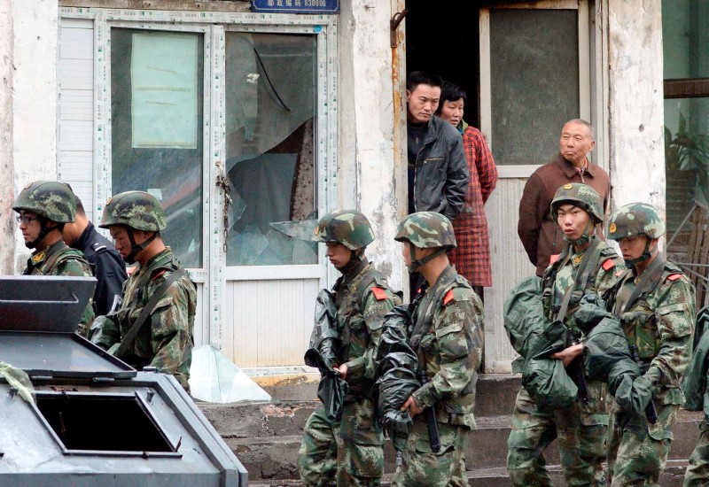 © Reuters. Paramilitary policemen patrol past a building, where a window was damaged by an explosion in Urumqi on Thursday, in the Xinjiang Uighur Autonomous Region