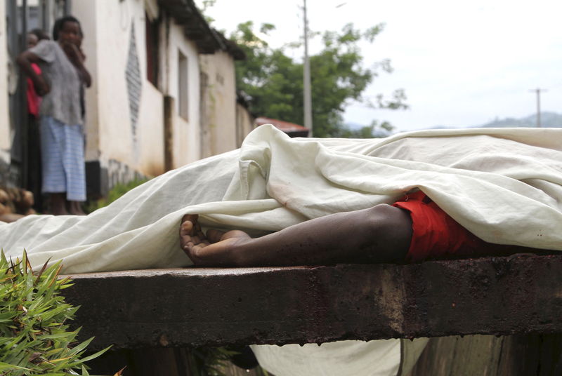 © Reuters. Residents look at the body of an unidentified man killed during gunfire, in the Nyakabiga neighbourhood of Burundi's capital Bujumbura