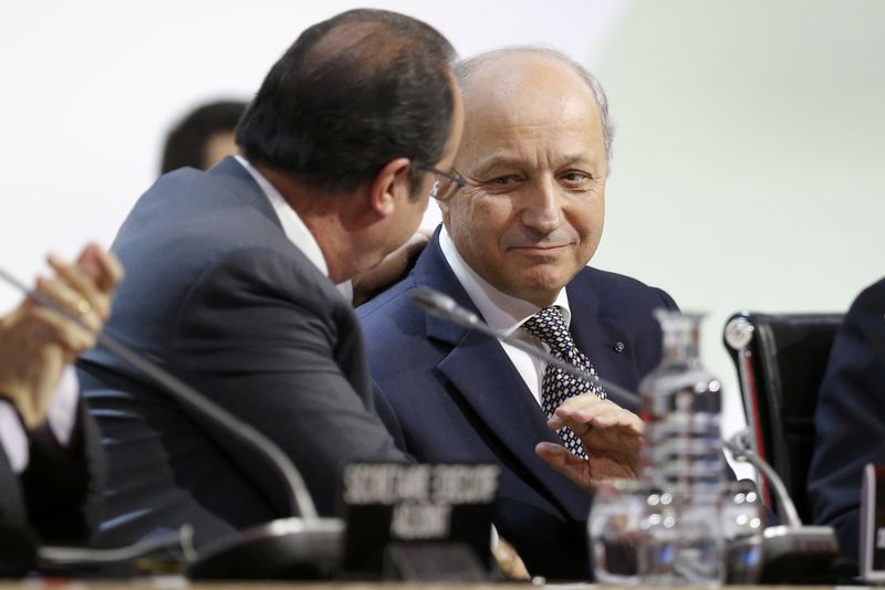 © Reuters. El ministro de Relaciones Exteriores francés, Laurent Fabius (derecha), habla con el presidente Francois Hollande durante la conferencia climática, en Le Bourget, cerca de París